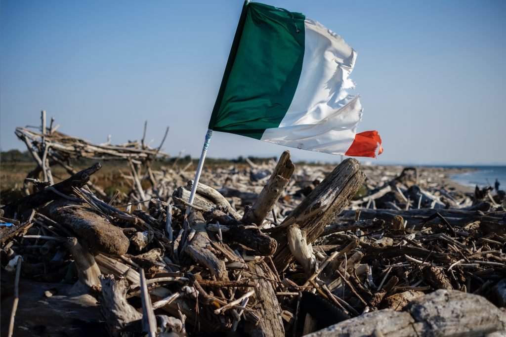 Bandiera italiana che sventola su tronchi abbandonati, Castelvolturno